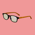 Load image into Gallery viewer, Eyeglasses with black frames and wooden arms on a pink background