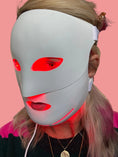 Load image into Gallery viewer, Person wearing a white face mask with red lights on a blurred indoor background