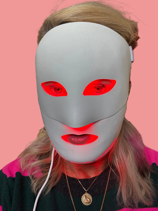 Person wearing a white mask with red eye holes in an indoor setting